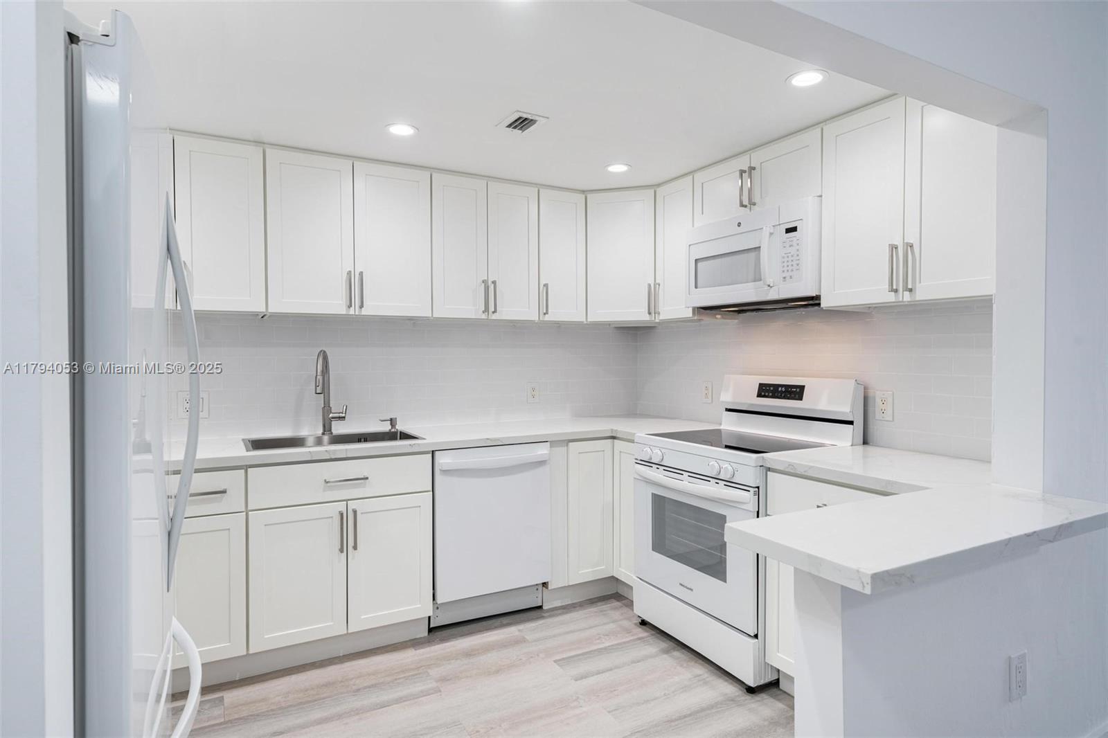 150 Southeast 25th Road, Unit 2H Miami, FL 33129 - Photo 4 of 15 a kitchen with white cabinets stainless steel appliances and sink