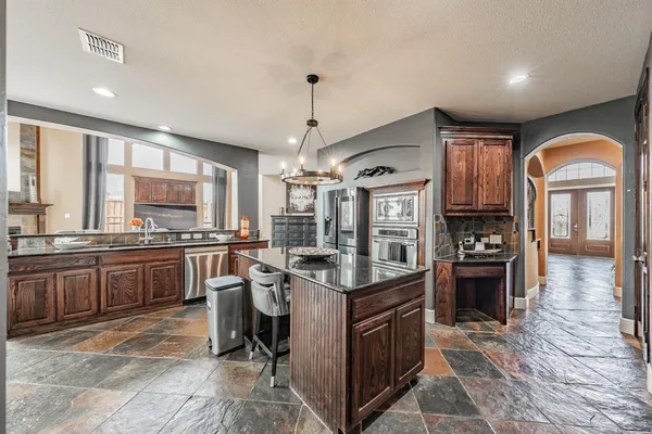 a kitchen with stainless steel appliances granite countertop a stove top oven a sink dishwasher a dining table and chairs with wooden floor