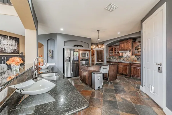 a room with stainless steel appliances kitchen island granite countertop a sink and a stove