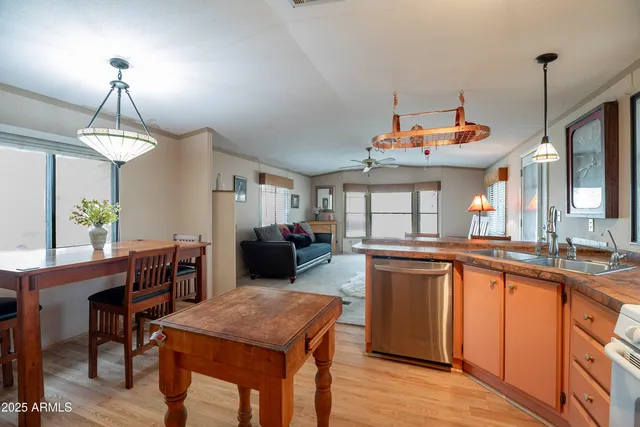 a kitchen with a stove a sink dishwasher a dining table and chairs with wooden floor