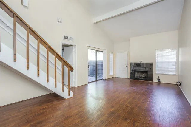 a view of an empty room with wooden floor and stairs