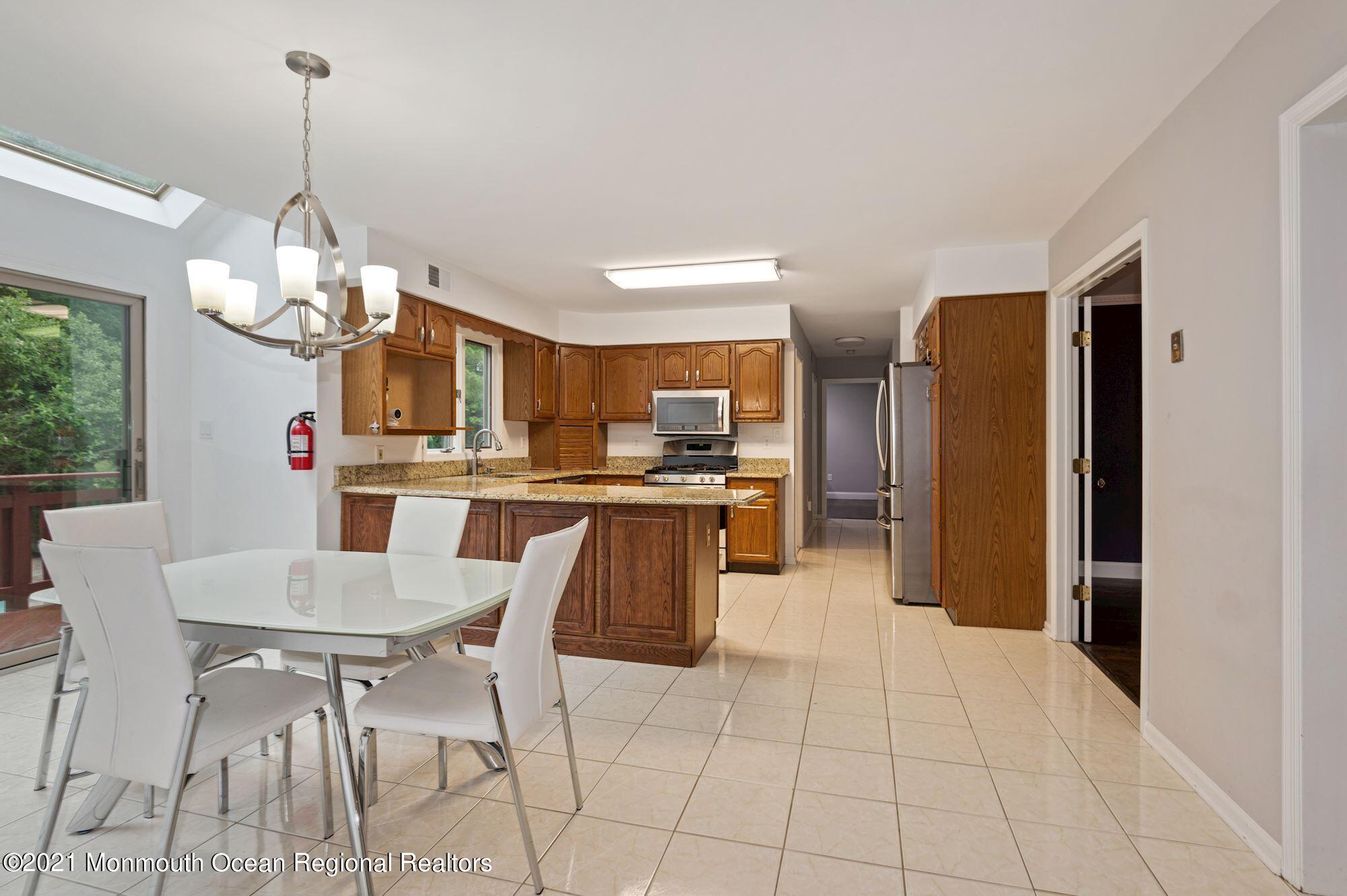 256 Nottingham Road Morganville, NJ 07751 - Photo 4 of 41 a kitchen with stainless steel appliances kitchen island granite countertop a refrigerator a stove a sink dishwasher and a dining table with wooden floor