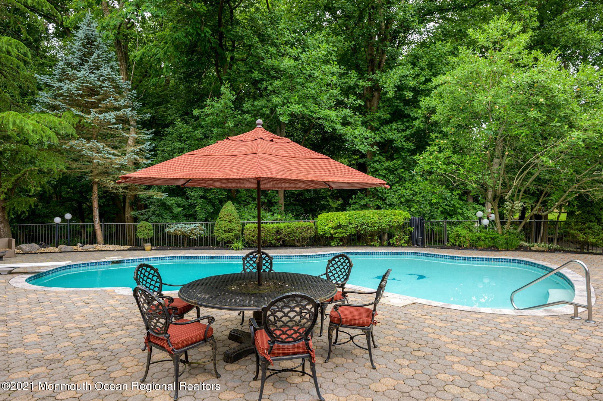 256 Nottingham Road Morganville, NJ 07751 - Photo 34 of 41 a patio with a table and chairs under an umbrella