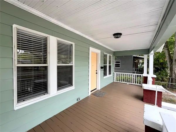 a view of a deck with couches and wooden floor next to a yard