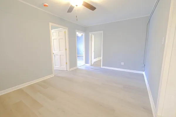 an empty room with a chandelier fan and windows