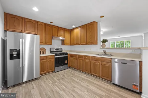 a kitchen with granite countertop a refrigerator stove top oven and sink