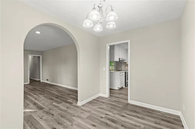 a view of a hallway with wooden floor and a kitchen