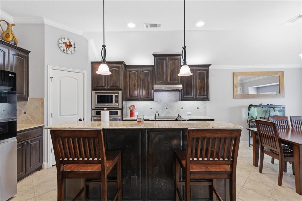 1105 Safrano Street Midlothian, TX 76065 - Photo 10 of 25 a kitchen with stainless steel appliances kitchen island granite countertop a dining table chairs and a refrigerator