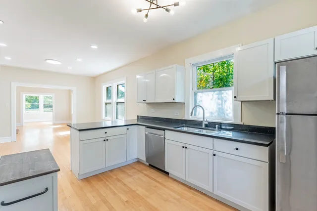 a kitchen with granite countertop white cabinets white appliances a sink and a window