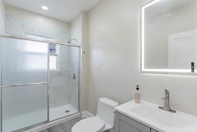 a bathroom with a shower sink vanity mirror and toilet