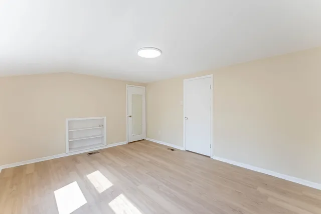 an empty room with wooden floor and natural light