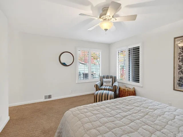 a bedroom with a bed couches chair and two large window