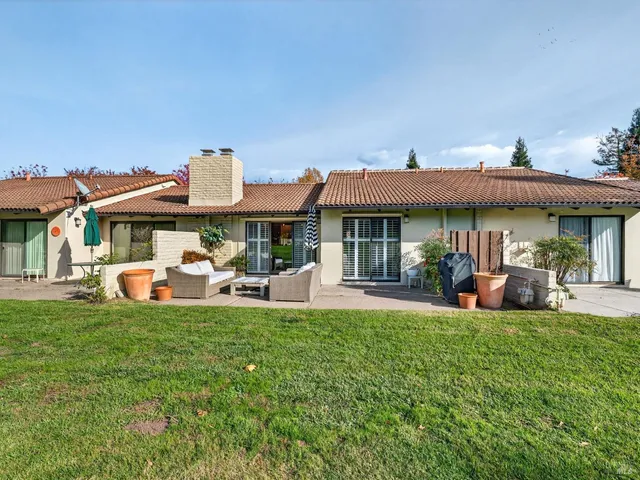 a view of a white house with a big yard and large trees