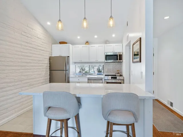 a kitchen with kitchen island a stove a table a sink refrigerator and microwave