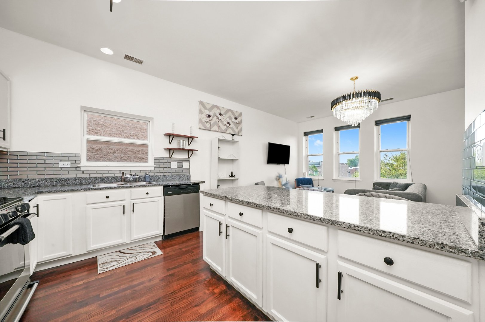 2432 West Harrison Street, Unit 3 Chicago, IL 60612 - Photo 21 of 32 a large white kitchen with granite countertop a sink dishwasher a dining table and chairs with wooden floor