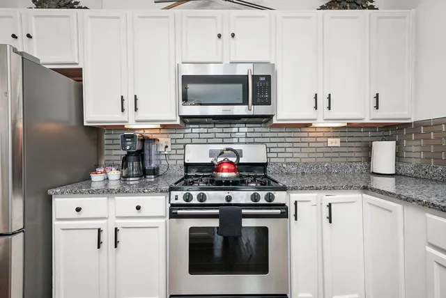 a kitchen with stainless steel appliances granite countertop a stove sink and cabinets