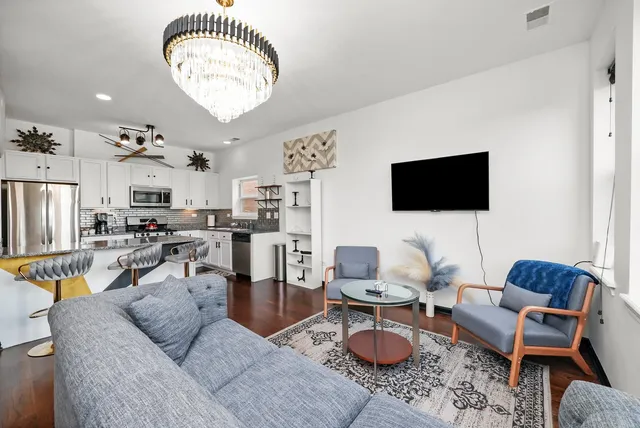 a living room with furniture a flat screen tv and kitchen view