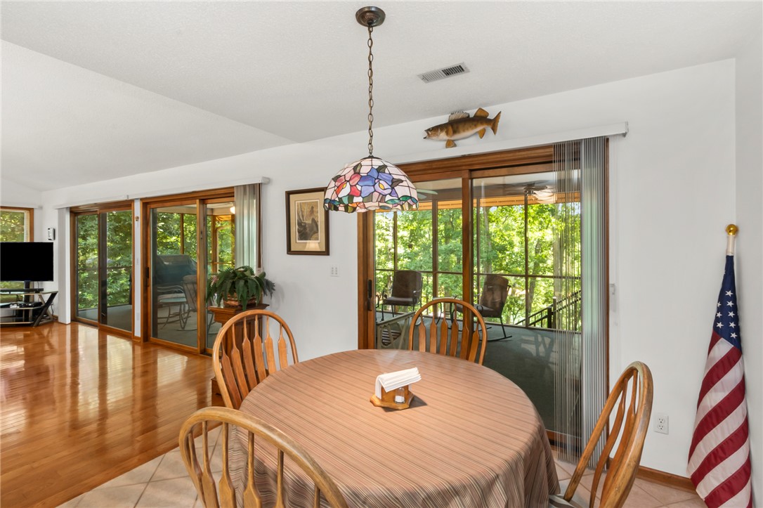 202 Plantation Point Anderson, SC 29625 - Photo 15 of 48 A vibrant Tiffany-style pendant light illuminates this inviting dining area, boasting glossy hardwood floors and expansive sliding doors to a scenic outdoor space.