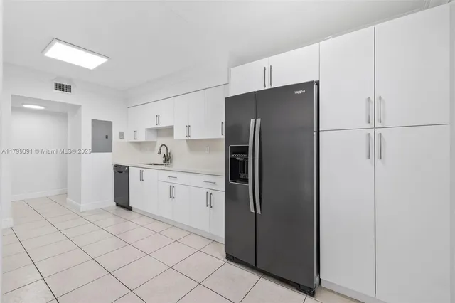 a kitchen with white cabinets and refrigerator