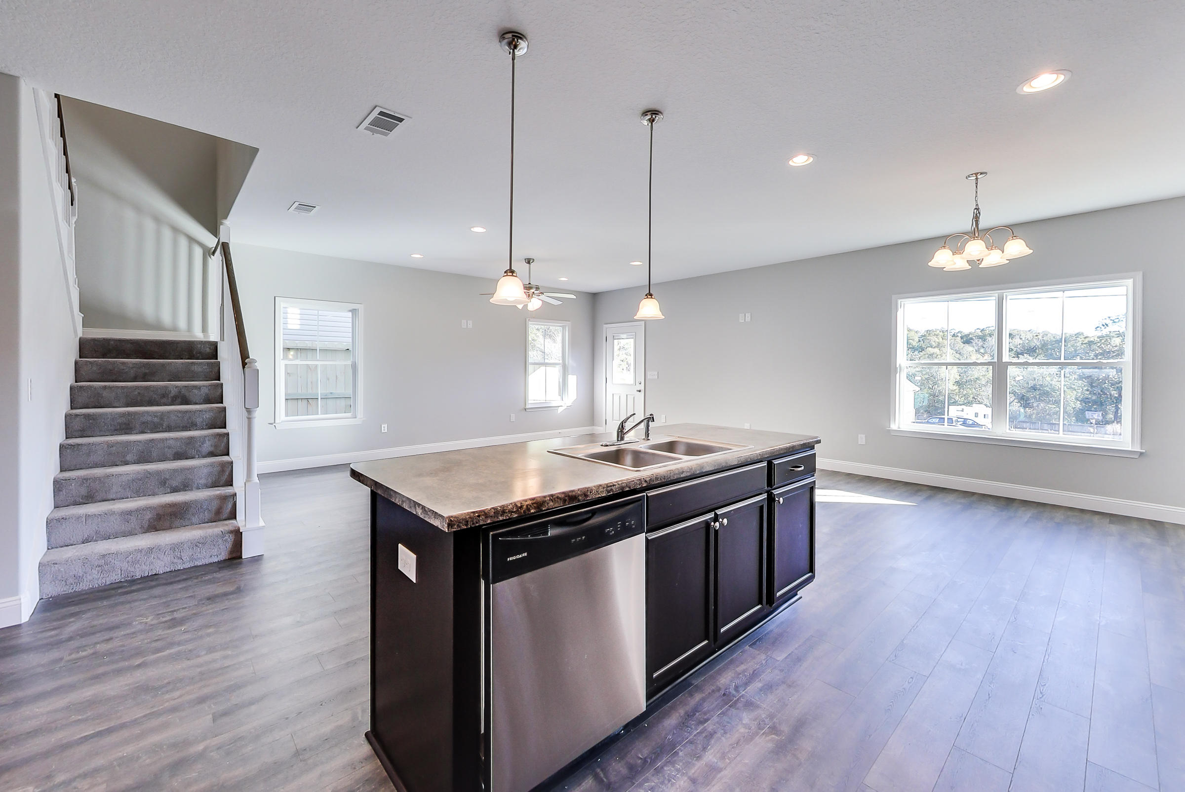 a kitchen with stainless steel appliances granite countertop a stove a sink a wooden floor and a large window