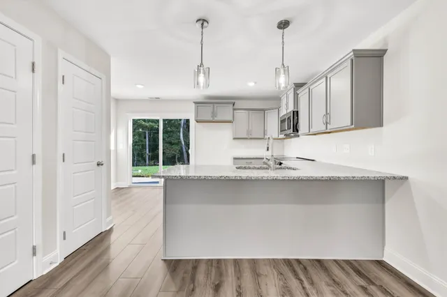 a kitchen with stainless steel appliances granite countertop a sink a stove and a wooden floors