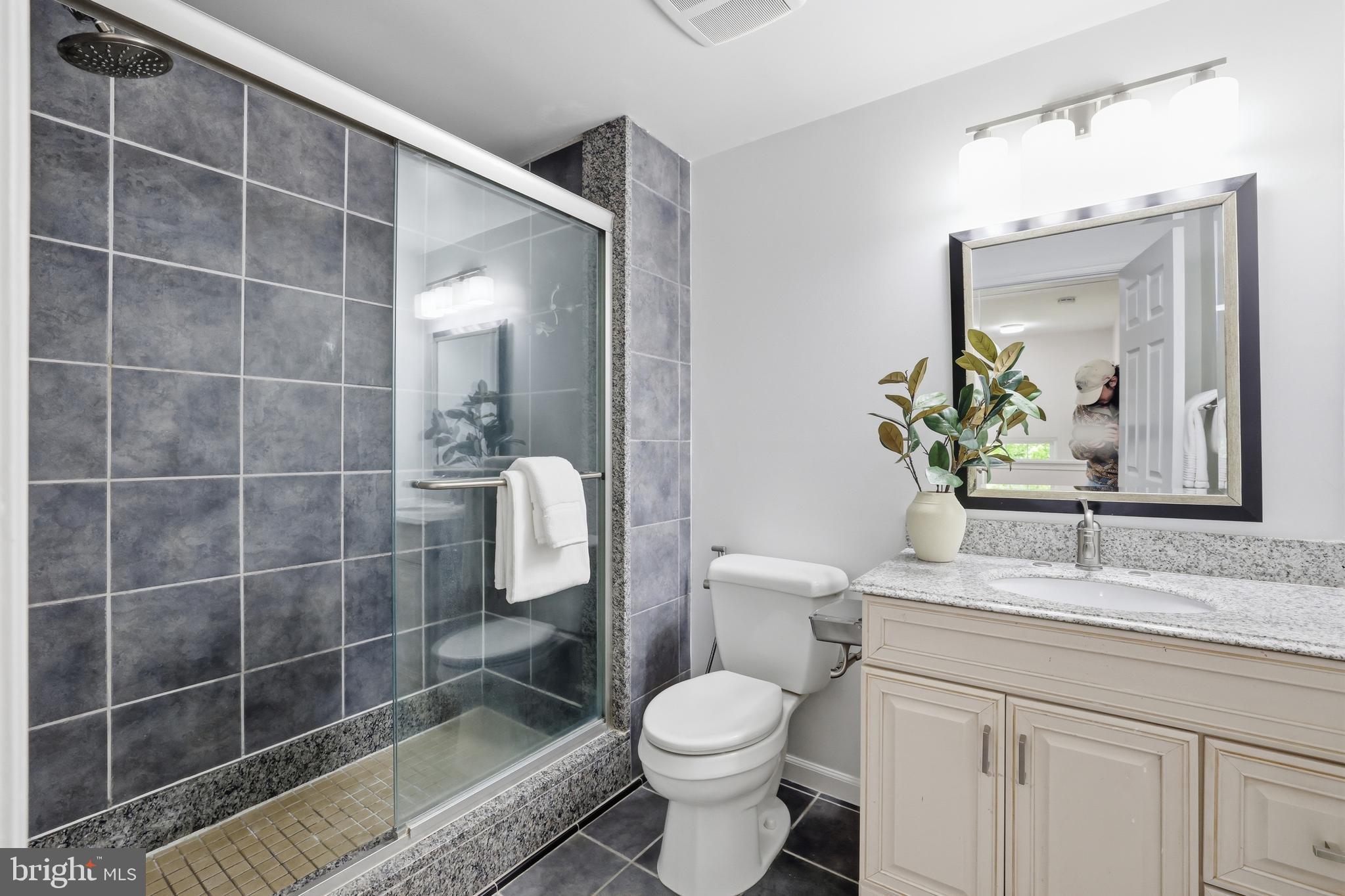 15029 Shamrock Ridge Road Silver Spring, MD 20906 - Photo 31 of 44 a bathroom with a granite countertop sink a toilet a mirror and shower