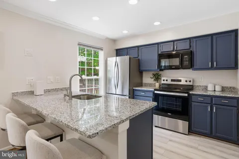 a kitchen with granite countertop kitchen island stainless steel appliances a sink stove and refrigerator