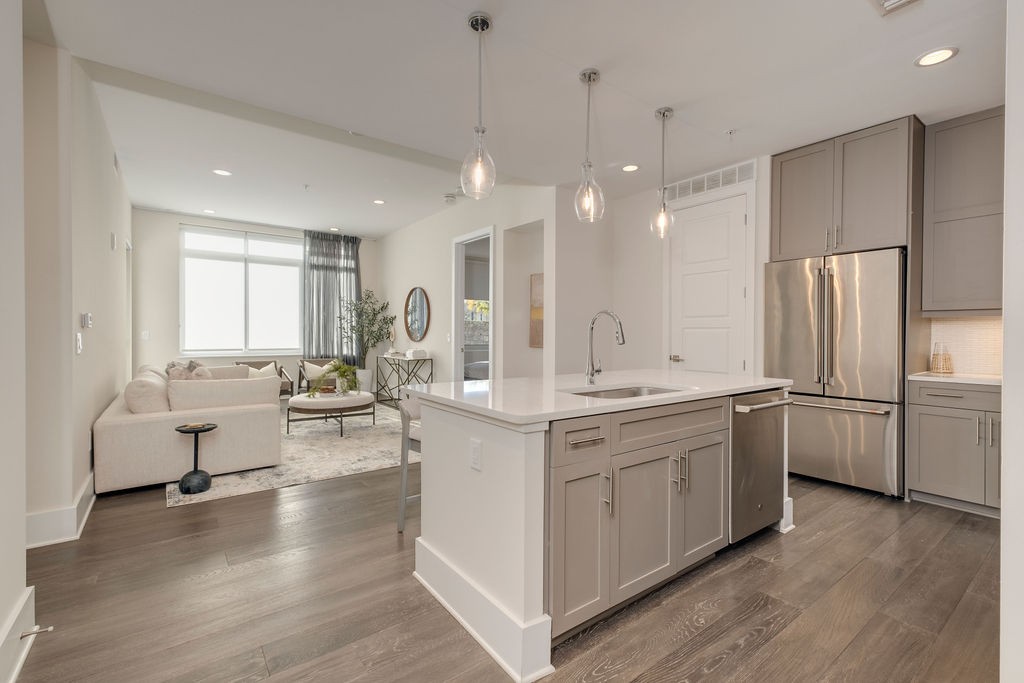 a large white kitchen with lots of counter space dining table and stainless steel appliances