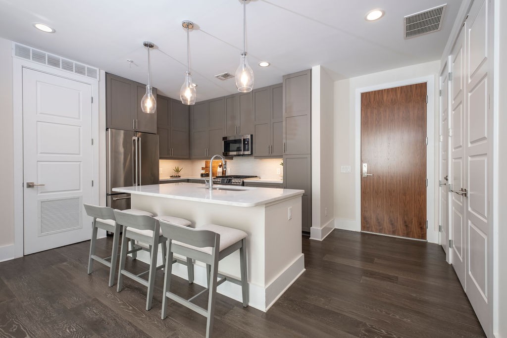 20 Rutledge Street, Unit 111 Nashville, TN 37210 - Photo 2 of 32 a kitchen with kitchen island a wooden floor and white appliances