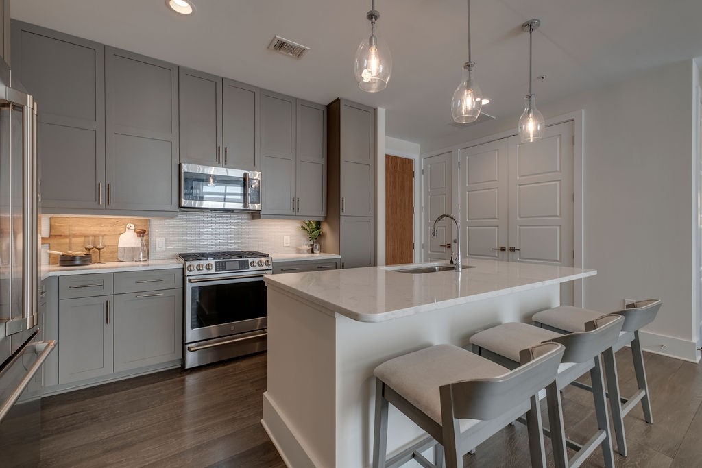 20 Rutledge Street, Unit 111 Nashville, TN 37210 - Photo 3 of 32 a large kitchen with granite countertop a stove a sink a table and chairs