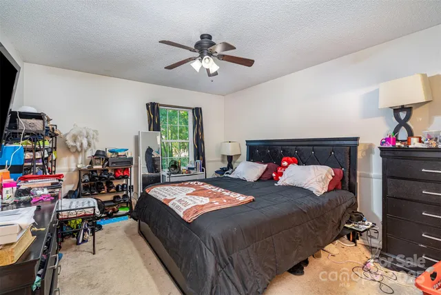 a bed room with a bed a dresser and a flat tv screen