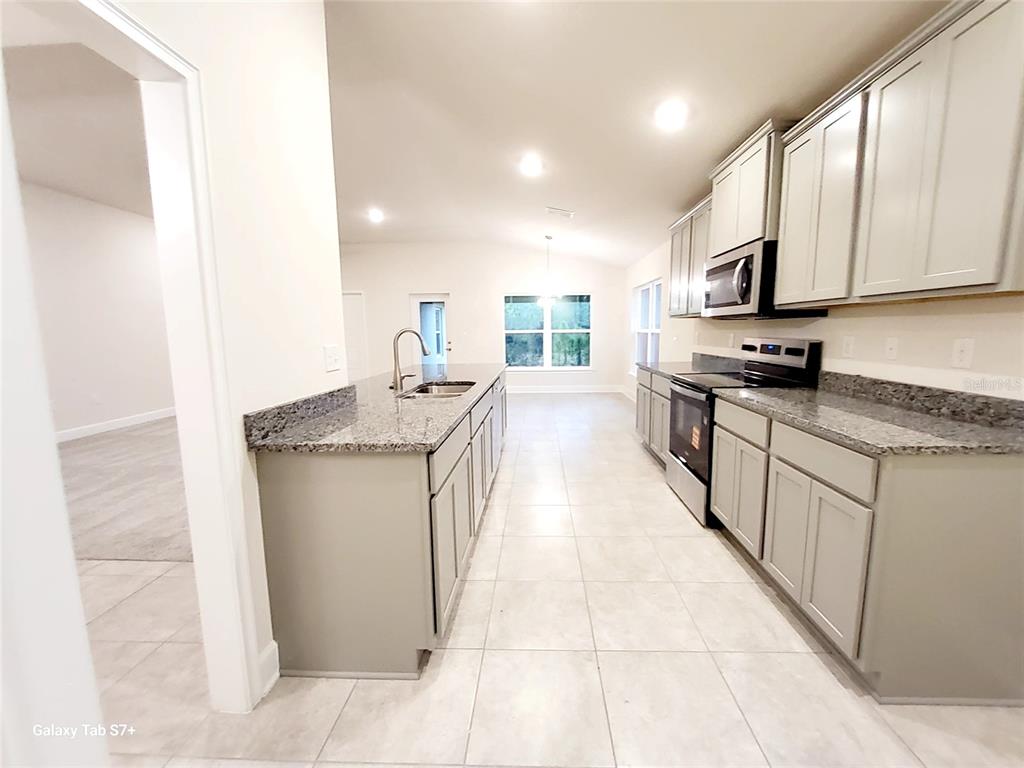 7560 Bent Tree Loop St. Cloud, FL 34773 - Photo 22 of 25 a kitchen with stainless steel appliances granite countertop a sink stove and cabinets