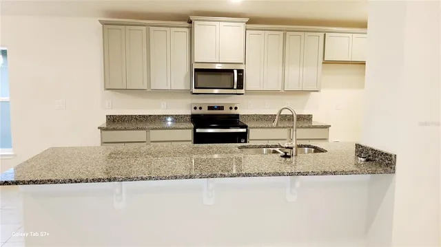 a kitchen with granite countertop a sink a stove and microwave