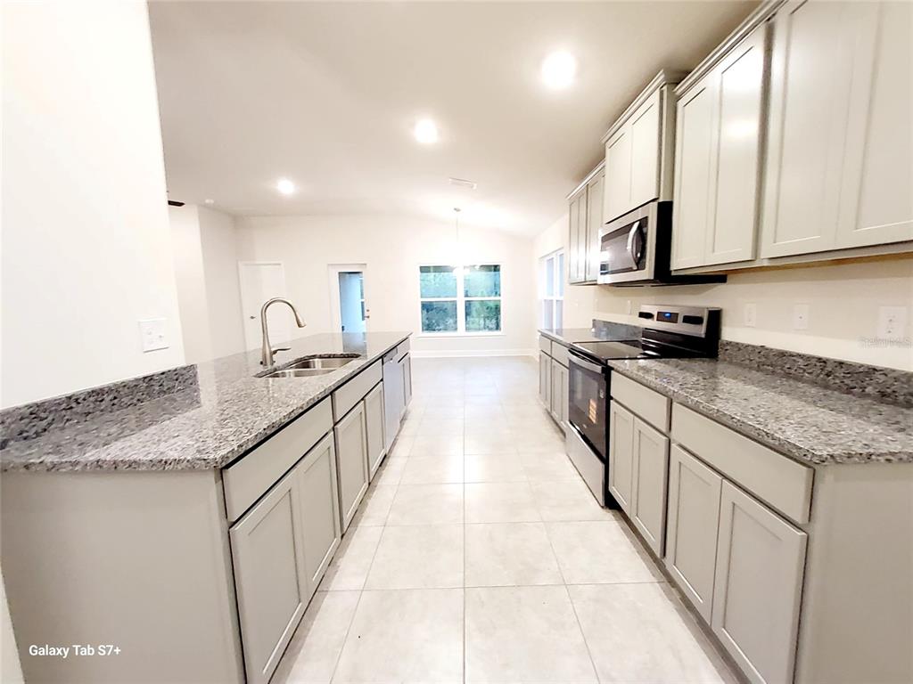 7560 Bent Tree Loop St. Cloud, FL 34773 - Photo 6 of 25 a kitchen with stainless steel appliances granite countertop a sink stove and cabinets