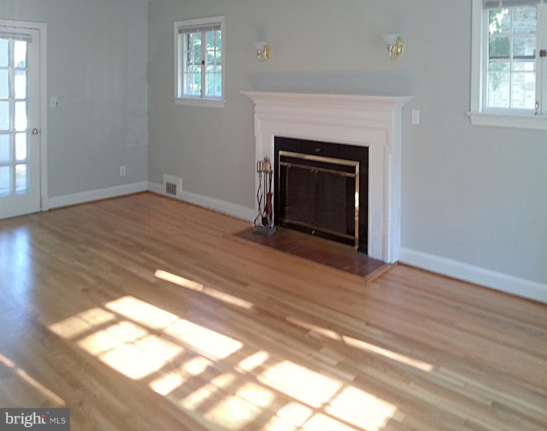 3130 38th Street Northwest Washington, DC 20016 - Photo 5 of 25 an empty room with wooden floor fireplace and windows