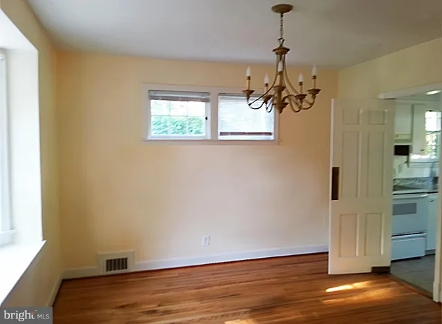 a view of a room with wooden floor electronic appliances and windows