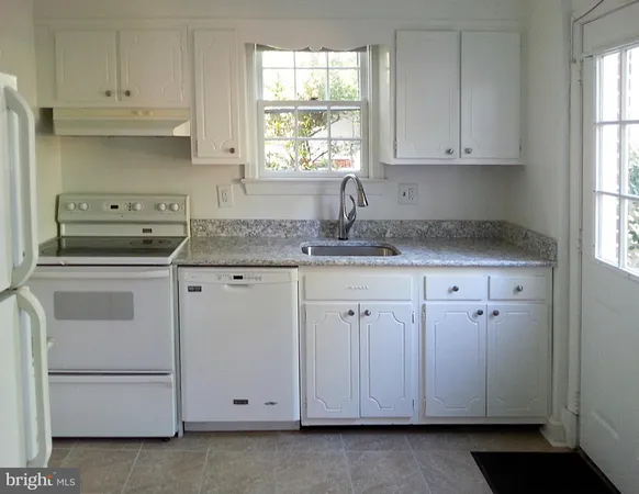 a kitchen with granite countertop white cabinets and white appliances