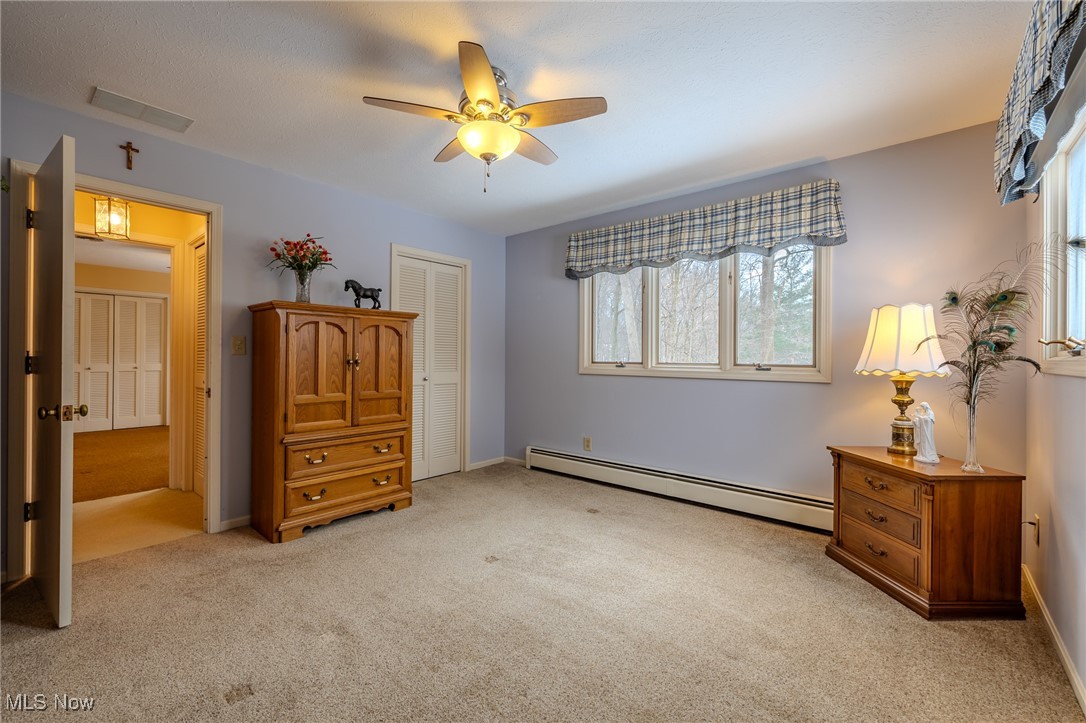 535 Barrington Ridge Road Painesville, OH 44077 - Photo 42 of 48 Bedroom with a baseboard heating unit, light carpet, ceiling fan, and a closet