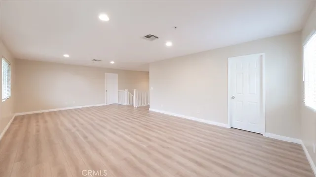 a view of an empty room with wooden floor and closet