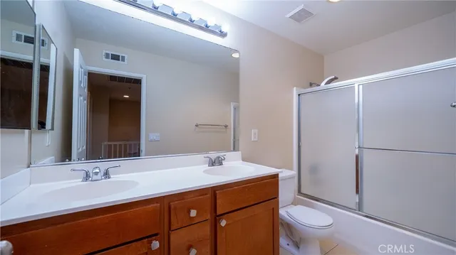a bathroom with a double vanity sink toilet and mirror