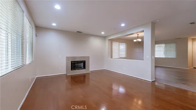 an empty room with wooden floor fireplace and windows
