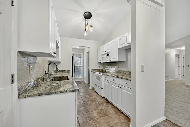 a kitchen with granite countertop a sink stove and cabinets