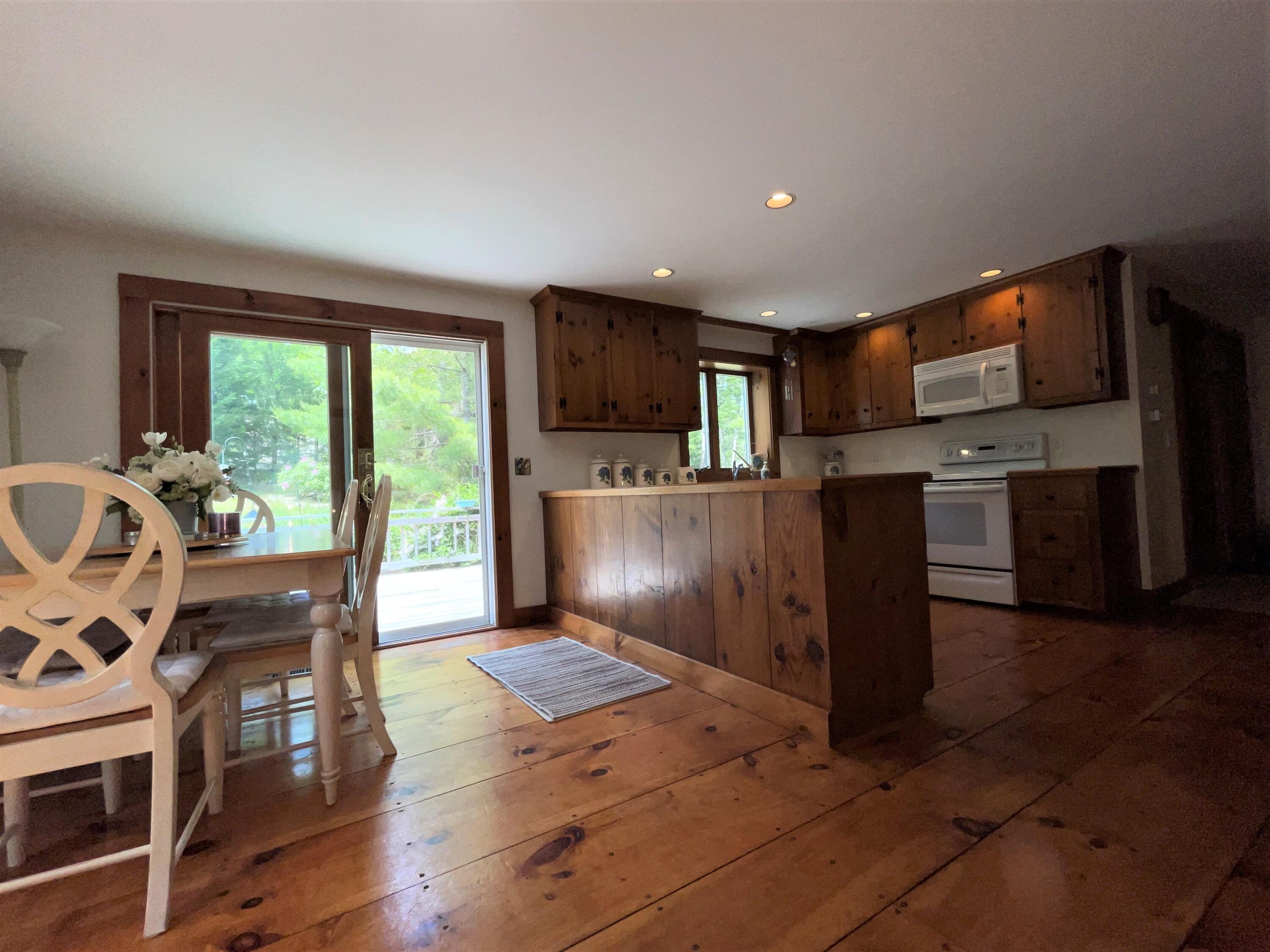 144 Long Road Harwich, MA 02645 - Photo 24 of 49 a kitchen with stainless steel appliances granite countertop a refrigerator a stove top oven and a dining table with wooden floor