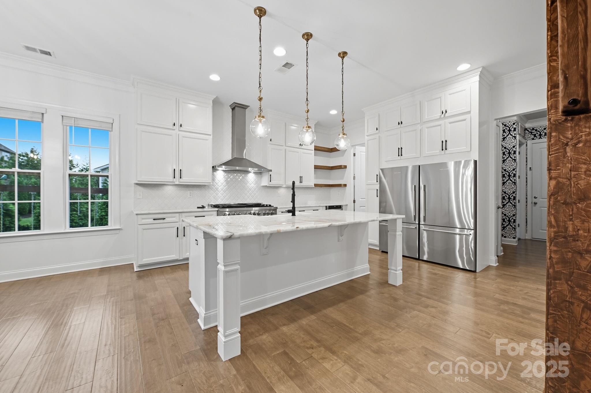 425 Cassia Court Tega Cay, SC 29708 - Photo 12 of 39 a kitchen with stainless steel appliances kitchen island granite countertop a refrigerator a stove a oven and white cabinets with wooden floor