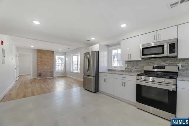 a kitchen with stainless steel appliances granite countertop a stove a sink and a refrigerator