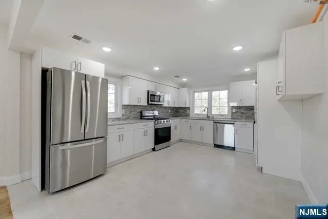 a kitchen with granite countertop white cabinets and stainless steel appliances