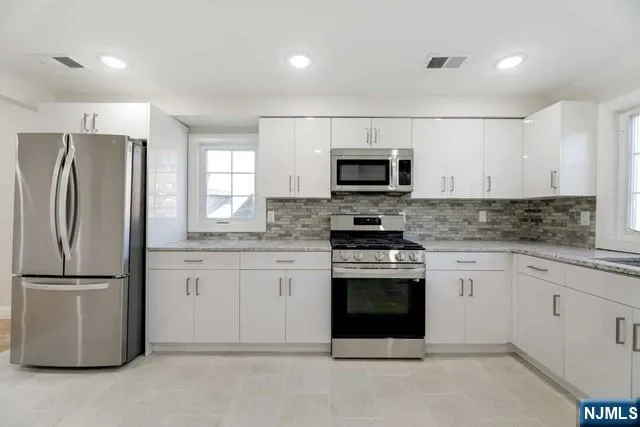 a kitchen with white cabinets and a window