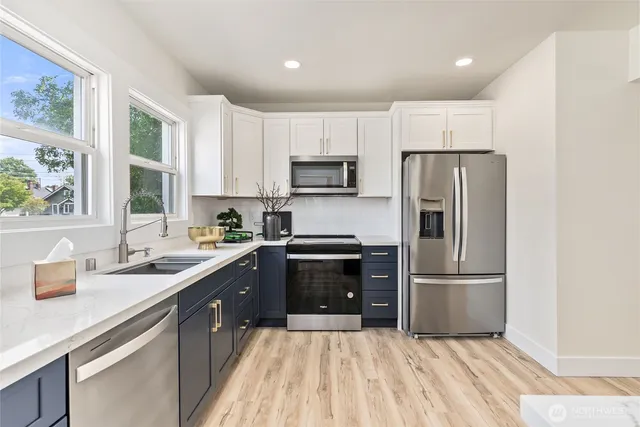 a kitchen with granite countertop a refrigerator oven a sink dishwasher and a stove with wooden floor