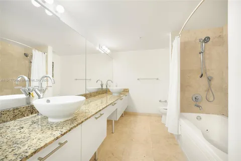 a bathroom with a granite countertop tub sink and mirror