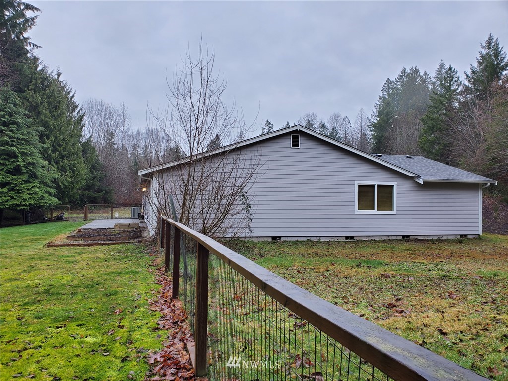 541 East Coulter Creek Road Belfair, WA 98528 - Photo 36 of 39 a backyard of a house with wooden fence and large trees